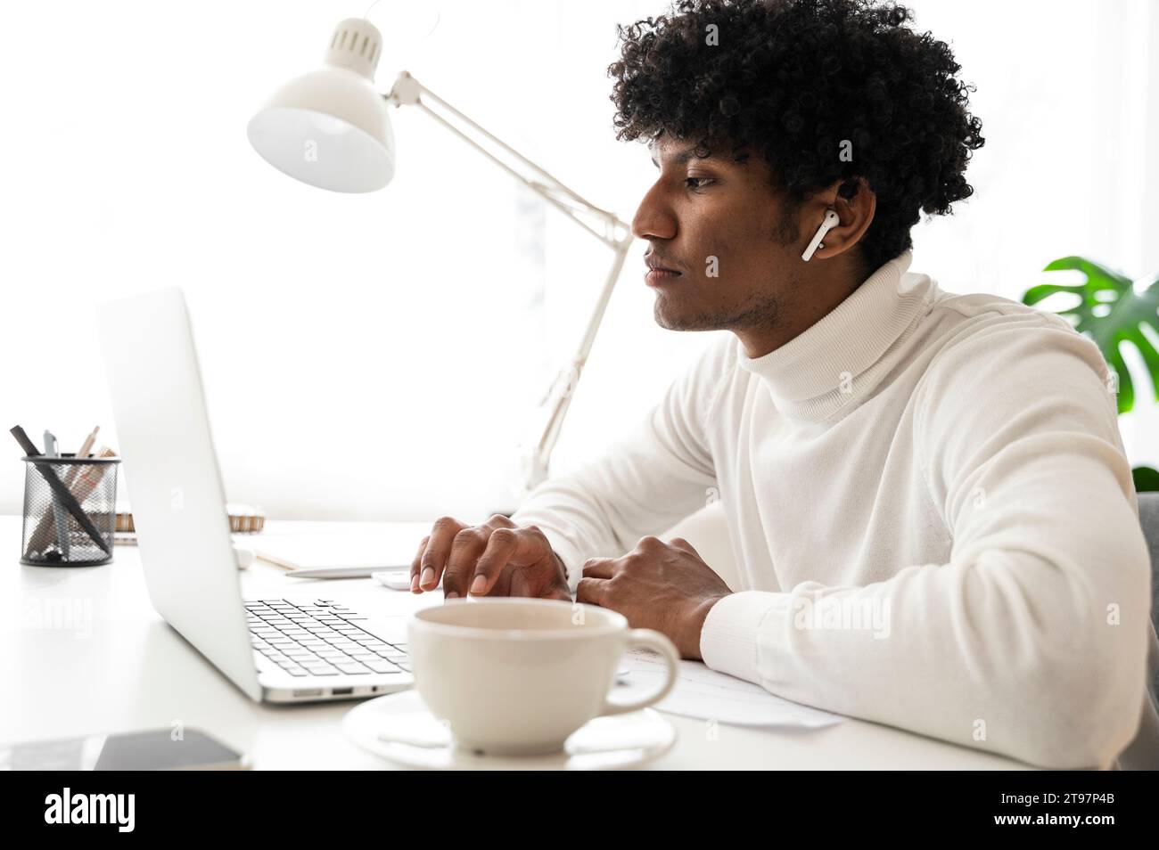 Geschäftsmann sitzt am Schreibtisch und arbeitet im Home Office am Laptop Stockfoto