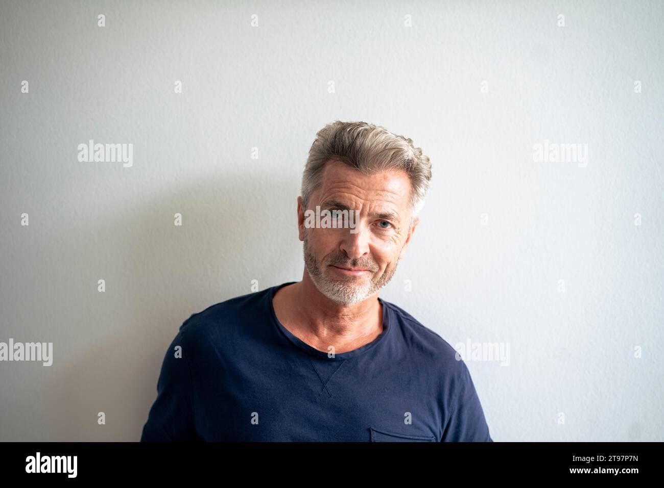 Lächelnder reifer Mann vor der weißen Wand Stockfoto