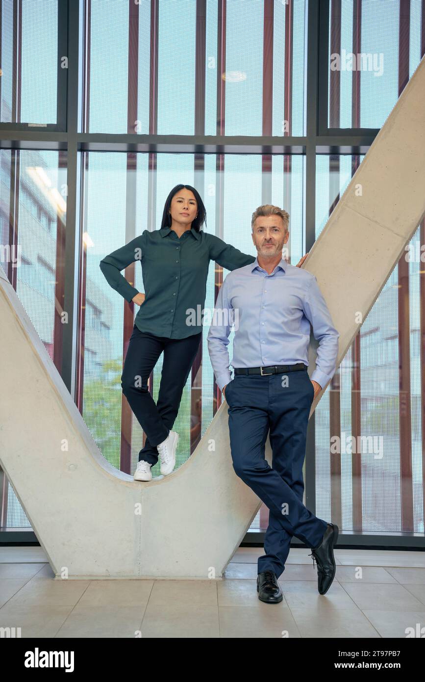 Geschäftsmann mit Geschäftsfrau, die auf einer architektonischen Säule steht Stockfoto