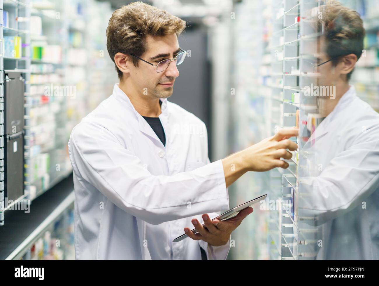 Apotheker untersucht Arzneimittelvorräte in Regalen in der Apotheke Stockfoto