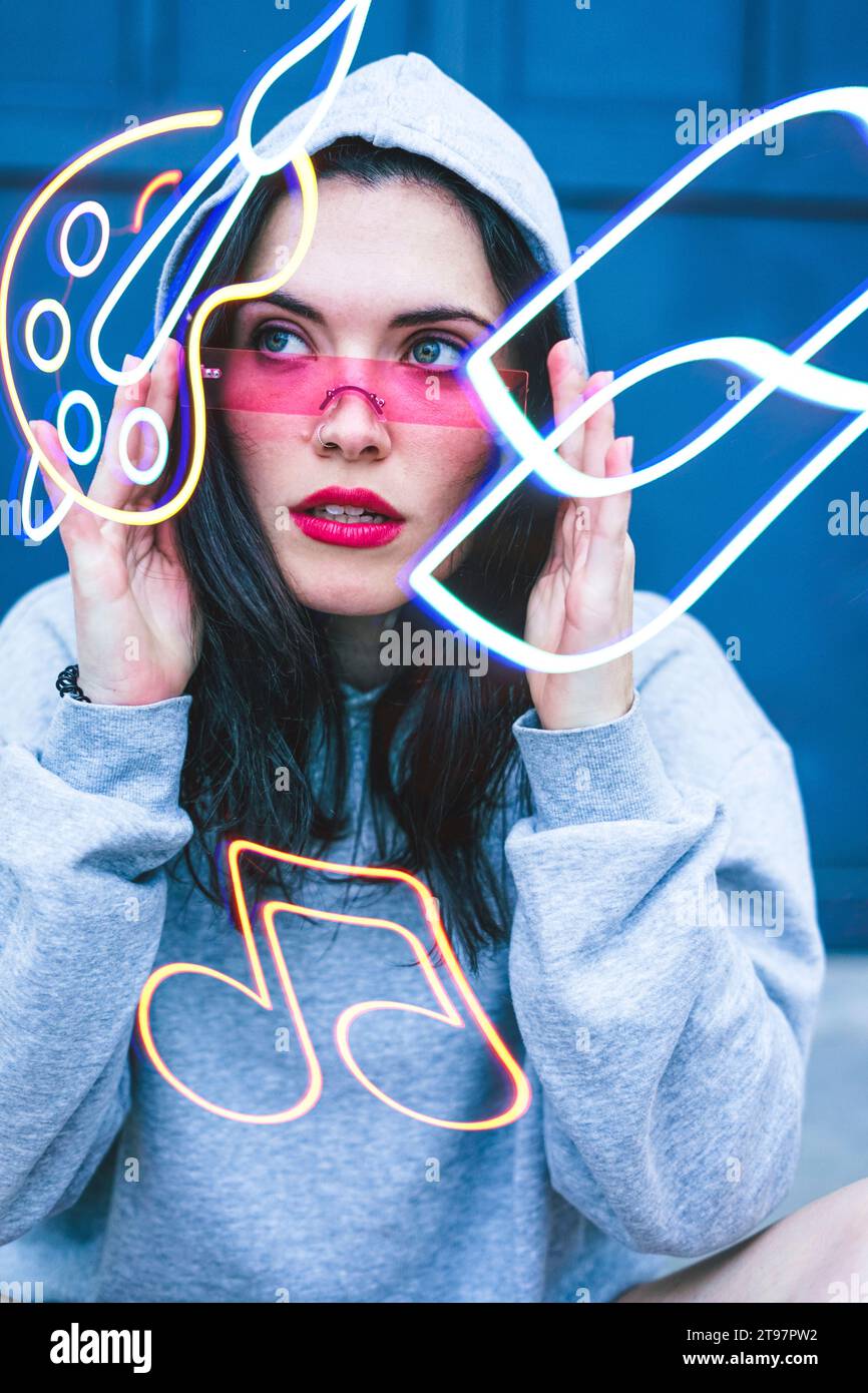 Eine junge Frau, die eine kluge Brille trägt und leuchtende Formen ansieht Stockfoto