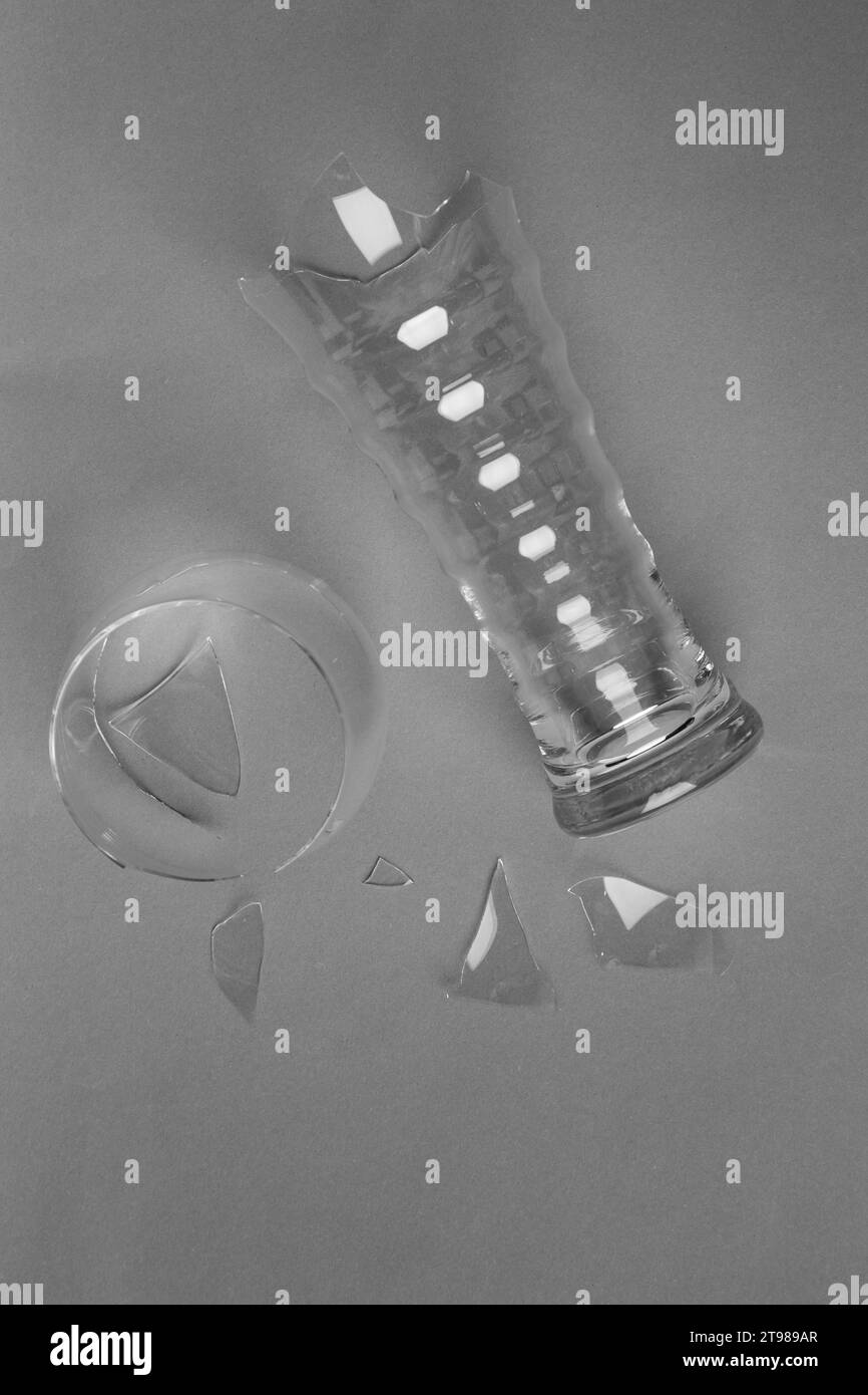 Gebrochenes Bierglas und Glasfragmente auf grauem Hintergrund, Draufsicht. Stockfoto
