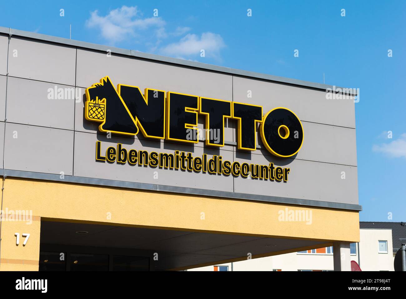 Schild des Netto Lebensmitteldiscounter (Lebensmitteldiscounter) auf einem Gebäude. Das schwarz-gelbe Logo mit dem Hund ist an der Wand. Werbung für Lebensmittelgeschäfte. Stockfoto