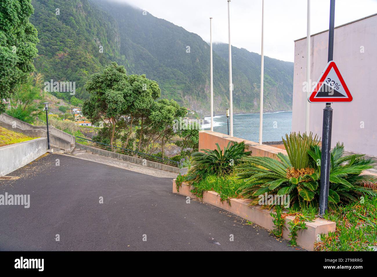 Gepflasterte Zufahrtsstraße zu den natürlichen Pools von Seixal auf Madeira Island. Vertikales Warnschild. Fahrbahnneigung mit 33 % Unebenheit. Stockfoto