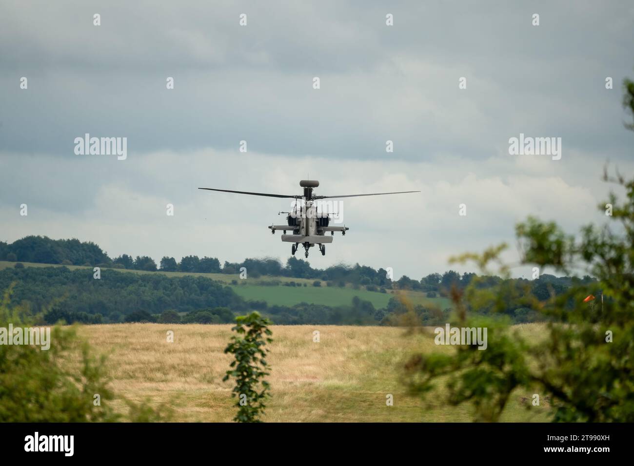 Nahaufnahme einer britischen Armee Boeing Apache Angriffshubschrauber AH64E AH-64E, die tief über der Sommerlandschaft schwebt Stockfoto
