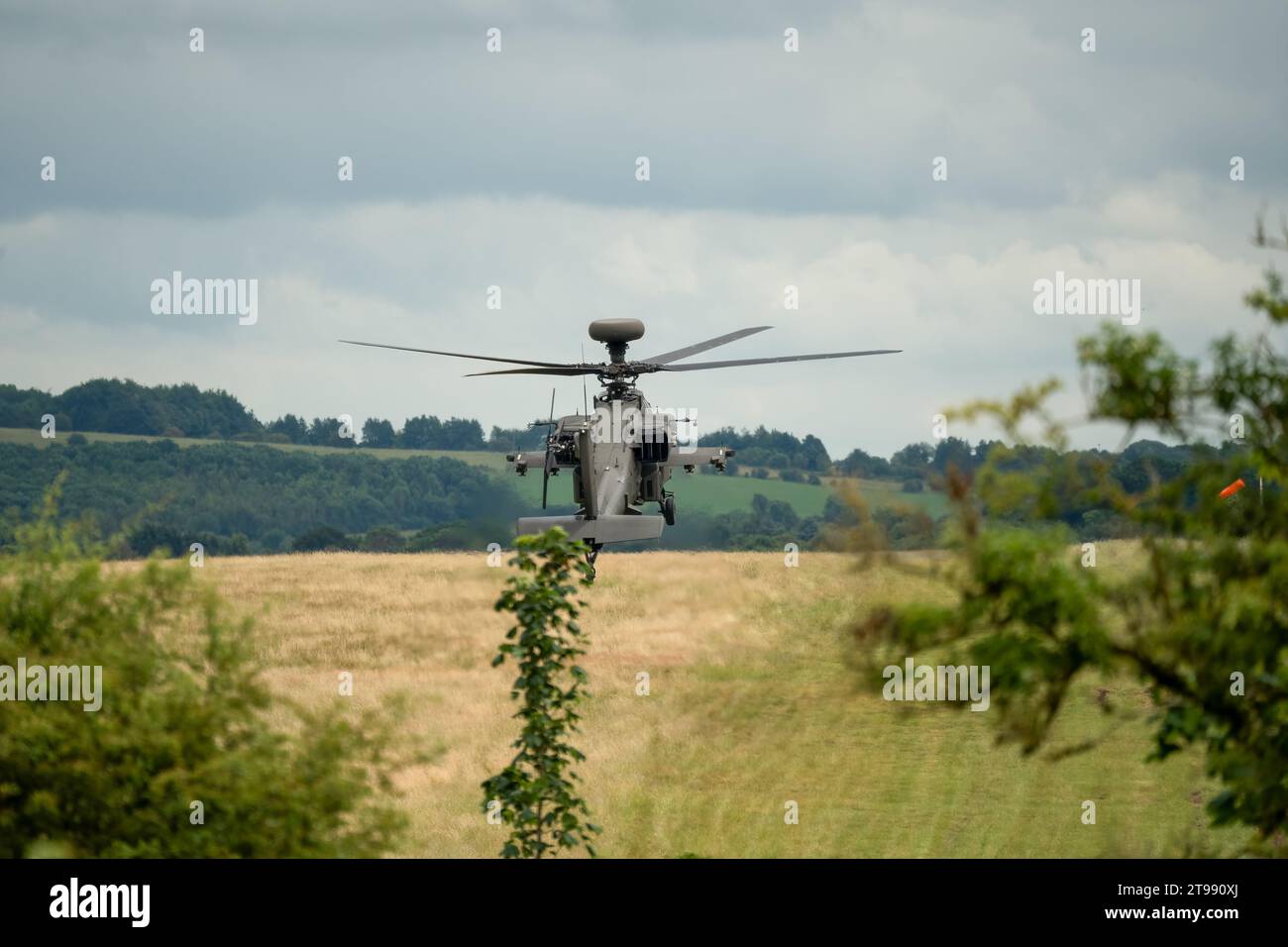 Nahaufnahme einer britischen Armee Boeing Apache Angriffshubschrauber AH64E AH-64E, die tief über der Sommerlandschaft schwebt Stockfoto