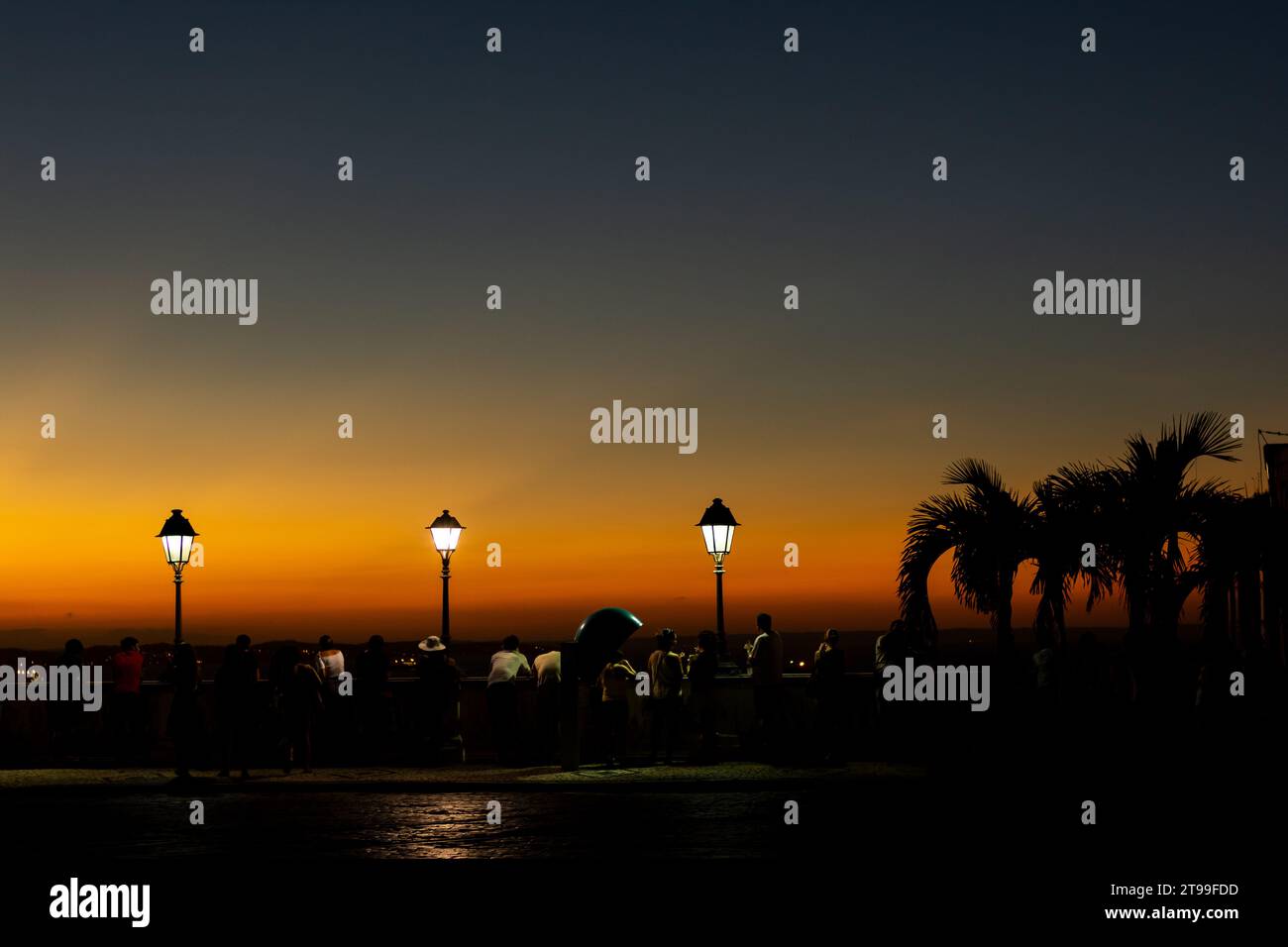 Salvador, Bahia, Brasilien - 21. April 2015: Silhouette von Touristen und Laternenpfosten bei Sonnenuntergang auf dem Platz Tome de Souza in der Stadt Salvador, Bahia. Stockfoto