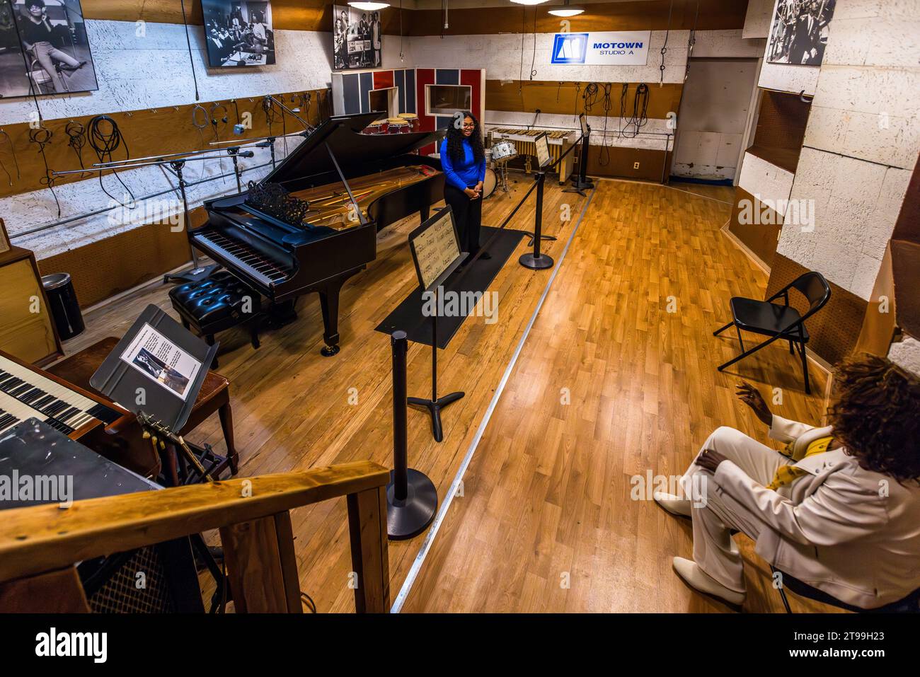 Ein Museumsführer steht an einem Musikpult im legendären Studio A von Motown Music, im Motown Museum Hitsville U.S.A. in Detroit, Michigan, Vereinigte Staaten, während ein Besucher in Weiß im Vordergrund sitzt. Im Hintergrund markiert ein Schild mit der Aufschrift „Motown Studio A“ den historischen Aufnahmeraum. Die Motown Studios befinden sich in einer Reihe von Wohnhäusern im Boston-Edison Historic District von Detroit. Stockfoto