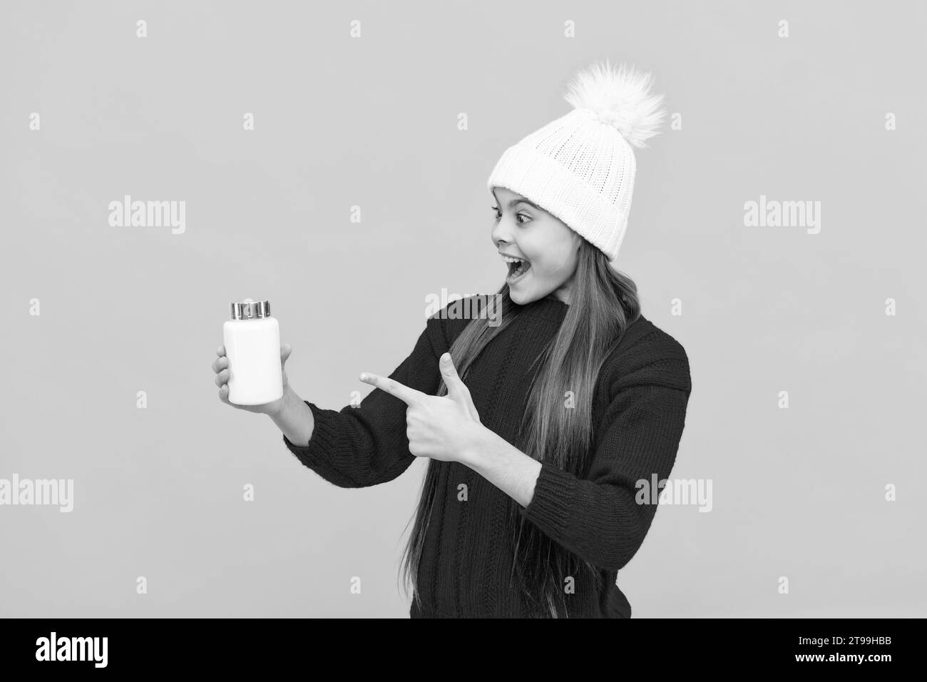 Staunte Kind in Hut zeigen Finger auf Vitamine auf gelbem Hintergrund, Apotheken Stockfoto