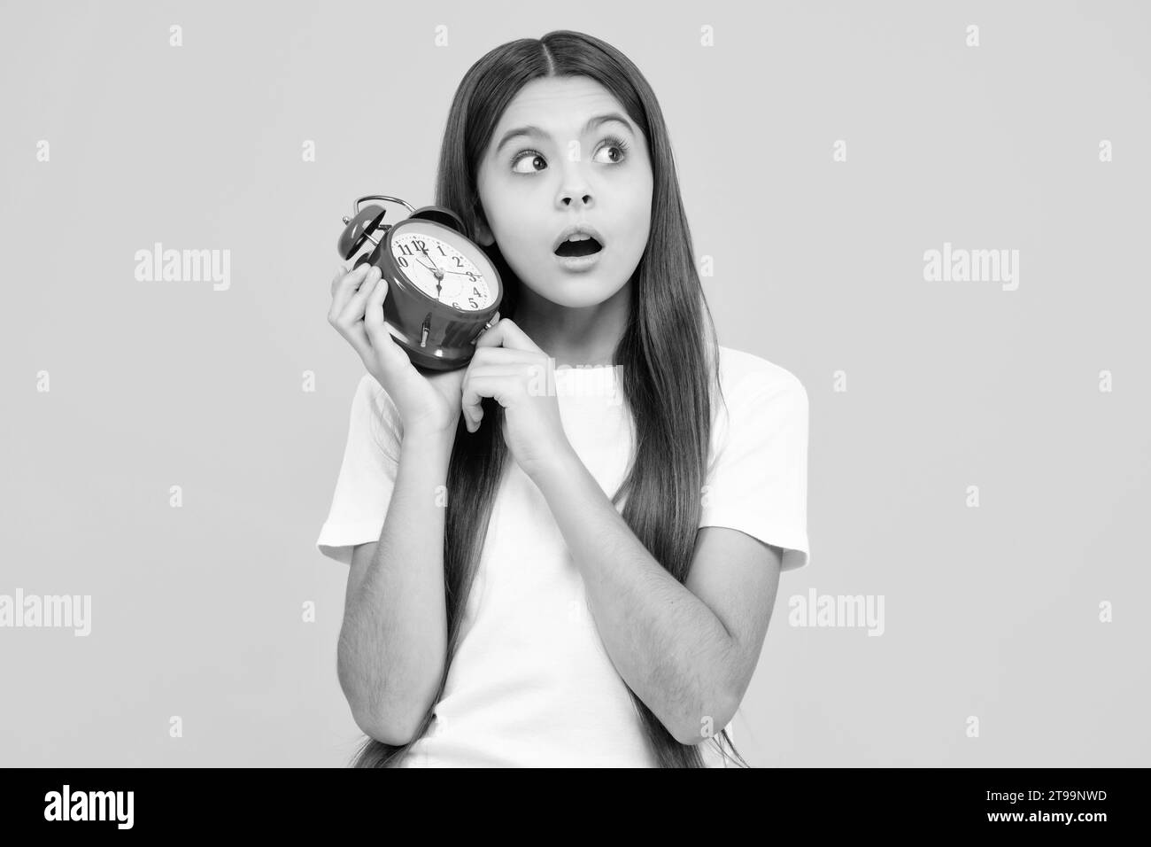 Teen Student Mädchen mit Uhr isoliert auf gelbem Hintergrund. Kind wieder in die Schule. Bildung und Zeitkonzept. Erstaunt überrascht Emotionen der jungen Stockfoto