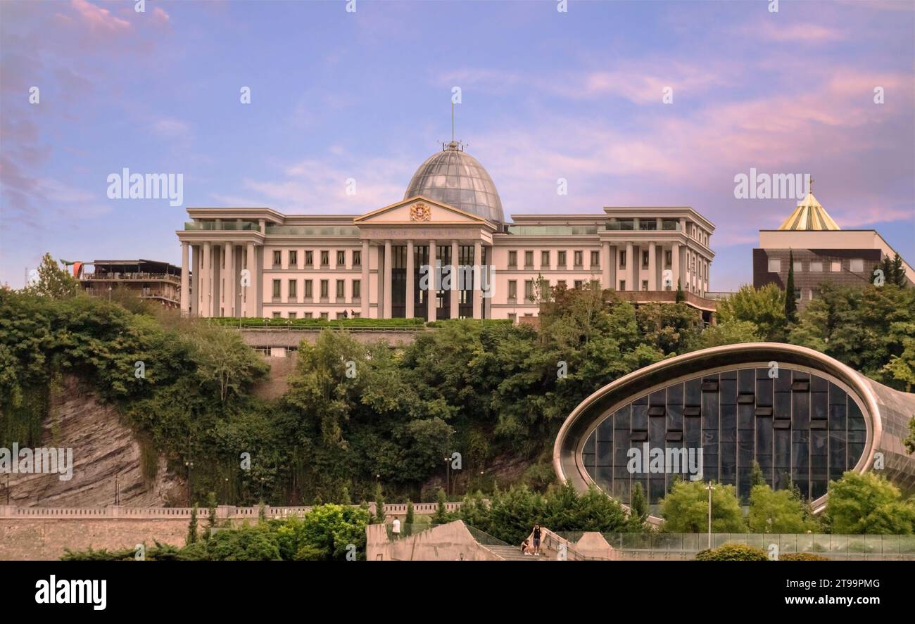 Blick auf den Sommersonnenuntergang des Zeremonialpalastes von Georgien, der sich über dem Nikoloz Baratashvili erhebt, mit der ovalen glasigen Vorderwand der Rike Konzerthalle im Stockfoto