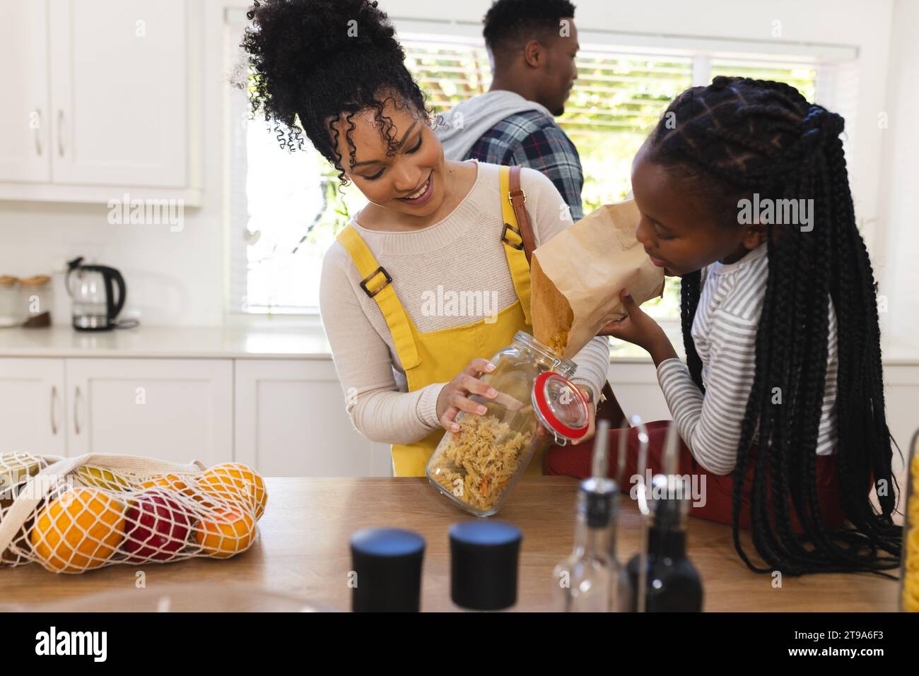 Glückliche afroamerikanische Mutter und Tochter, die Pasta in ein Glas in der Küche zu Hause gießen, Kopierraum. Ausdruck, Zweisamkeit, Mutterschaft, Kindheit, Stockfoto