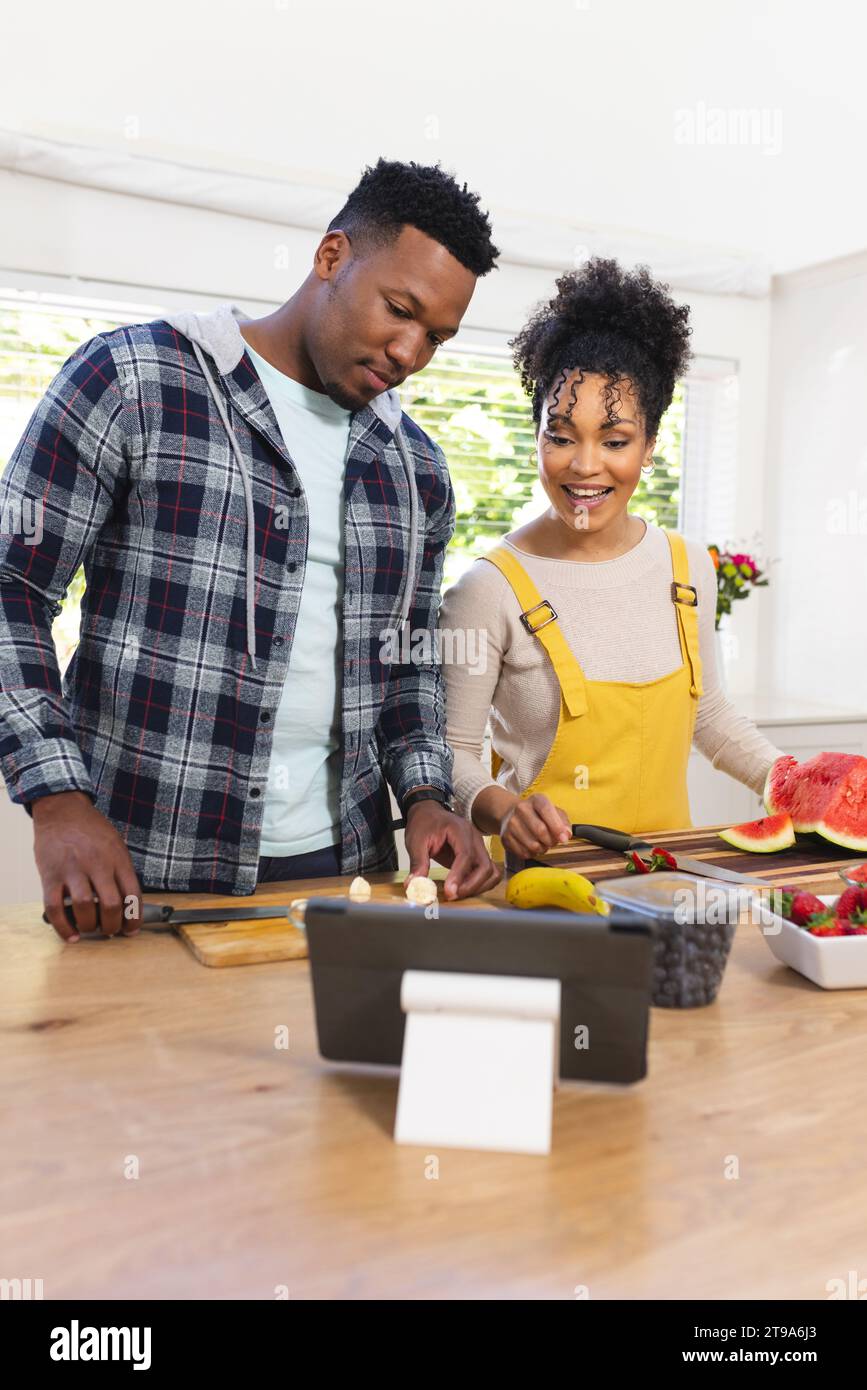 Glückliches afroamerikanisches Paar, das frischen Snack aus Früchten zubereitet, in der Küche zu Hause, Kopierraum. Miteinander, Essen und Trinken, Leben und Gesundheit Stockfoto