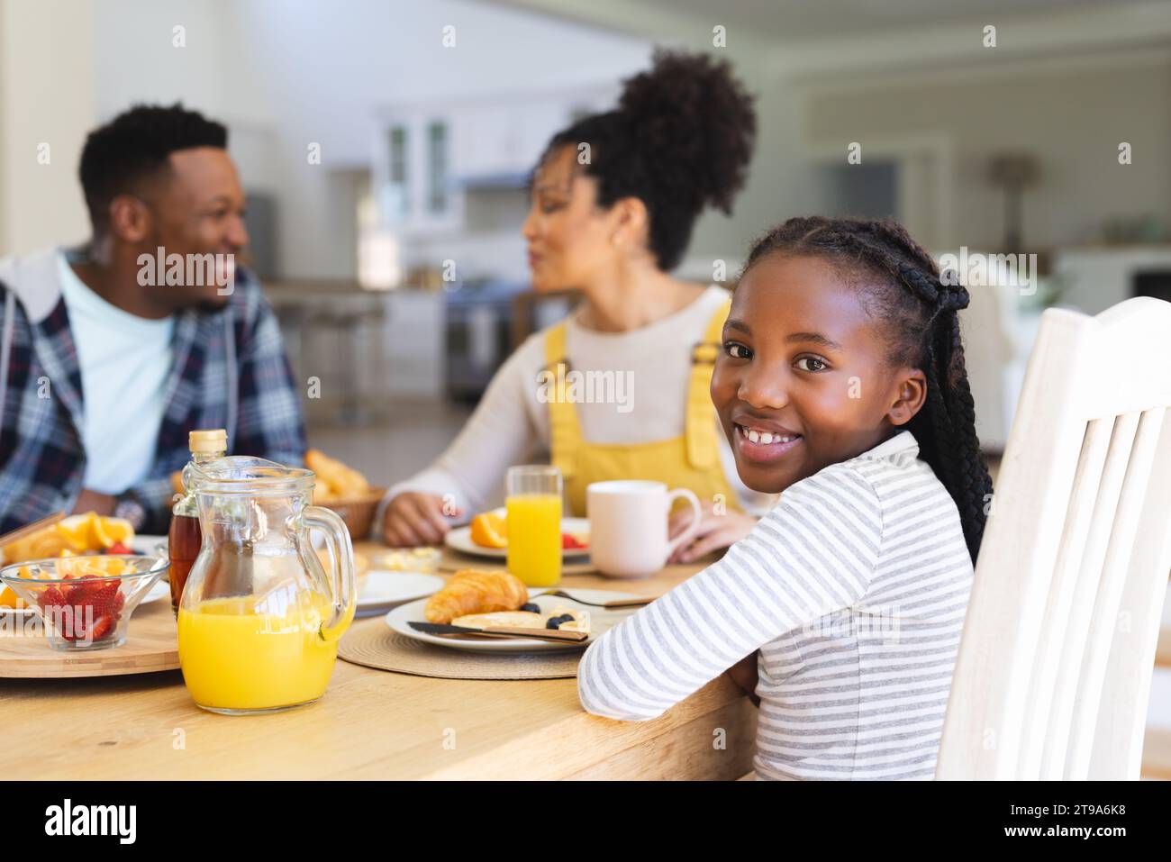 Glückliches afroamerikanisches Mädchen, das am Tisch sitzt, einen Snack mit der Familie zu Hause hat, Kopierraum. Zweisamkeit, Elternschaft, Kindheit, Essen und Trinken, dom Stockfoto