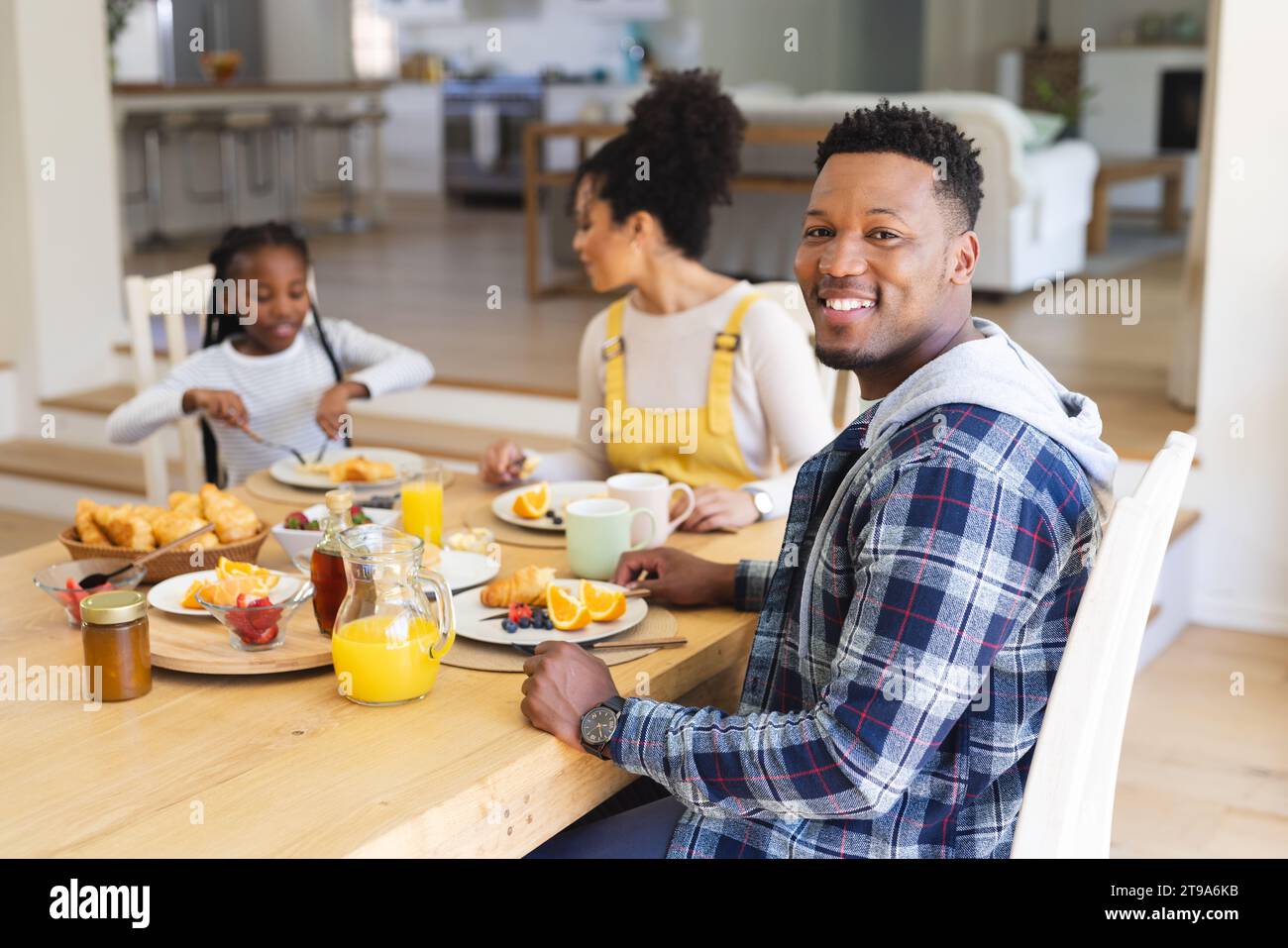 Glücklicher afroamerikanischer Mann, der am Tisch sitzt, einen Snack mit der Familie zu Hause hat, Kopierraum. Zweisamkeit, Elternschaft, Kindheit, Essen und Trinken, Kuppel Stockfoto