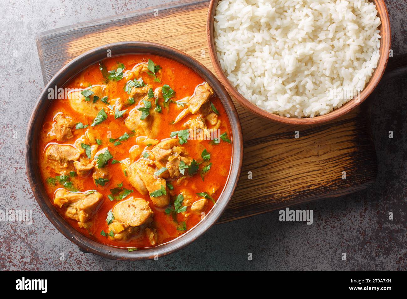 Chicken Lahori ist ein traditionelles pakistanisches Hühnercurry aus der Stadt Lahore, serviert mit Reis-Nahaufnahme auf dem Holzbrett auf dem Tisch. Hor Stockfoto