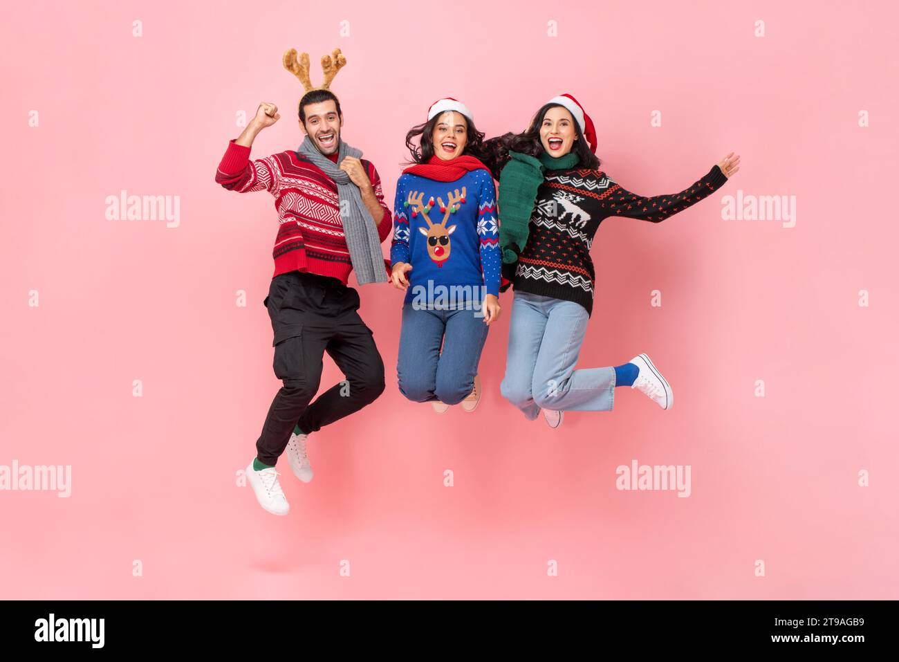 Gruppe glücklicher männlicher und weiblicher Freunde in Weihnachtskleidung, die in rosa Farbe springen, isolierte Hintergrundaufnahme im Studio Stockfoto