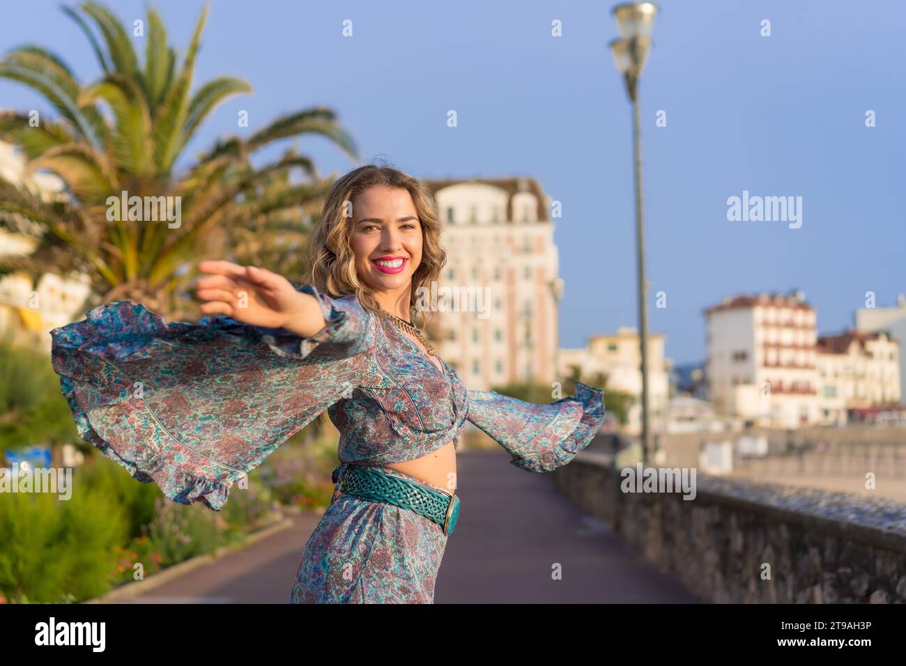 Glückliche Frau im blauen Sommerkleid, die beim Gehen auf der Straße tanzt Stockfoto