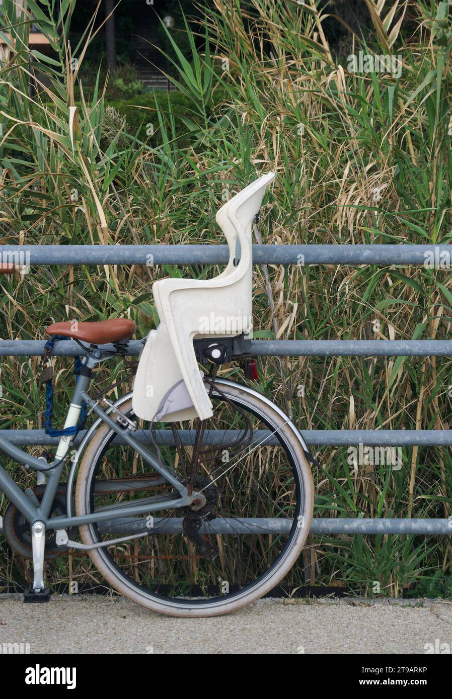 Vintage-Fahrrad mit Kindersitz, der an einem Geländer befestigt ist Stockfoto