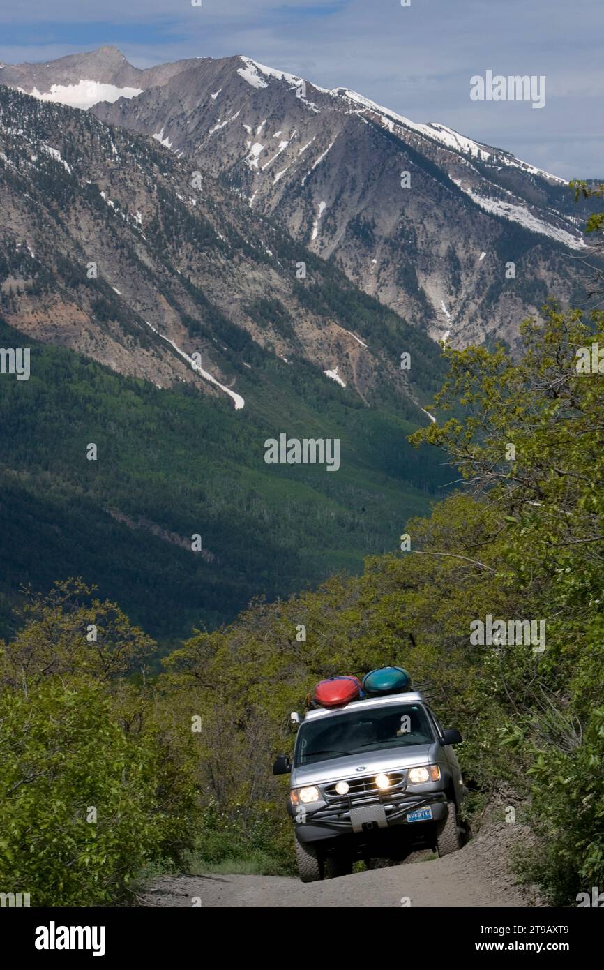 Ein Geländewagen, der eine Allradstraße mit Bergen im Hintergrund hinauffährt. Stockfoto