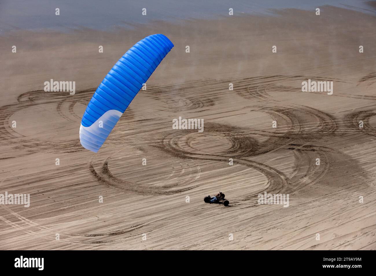 Ein Kite-Buggy rollt durch Formen und Texturen im Sand am Strand. Stockfoto