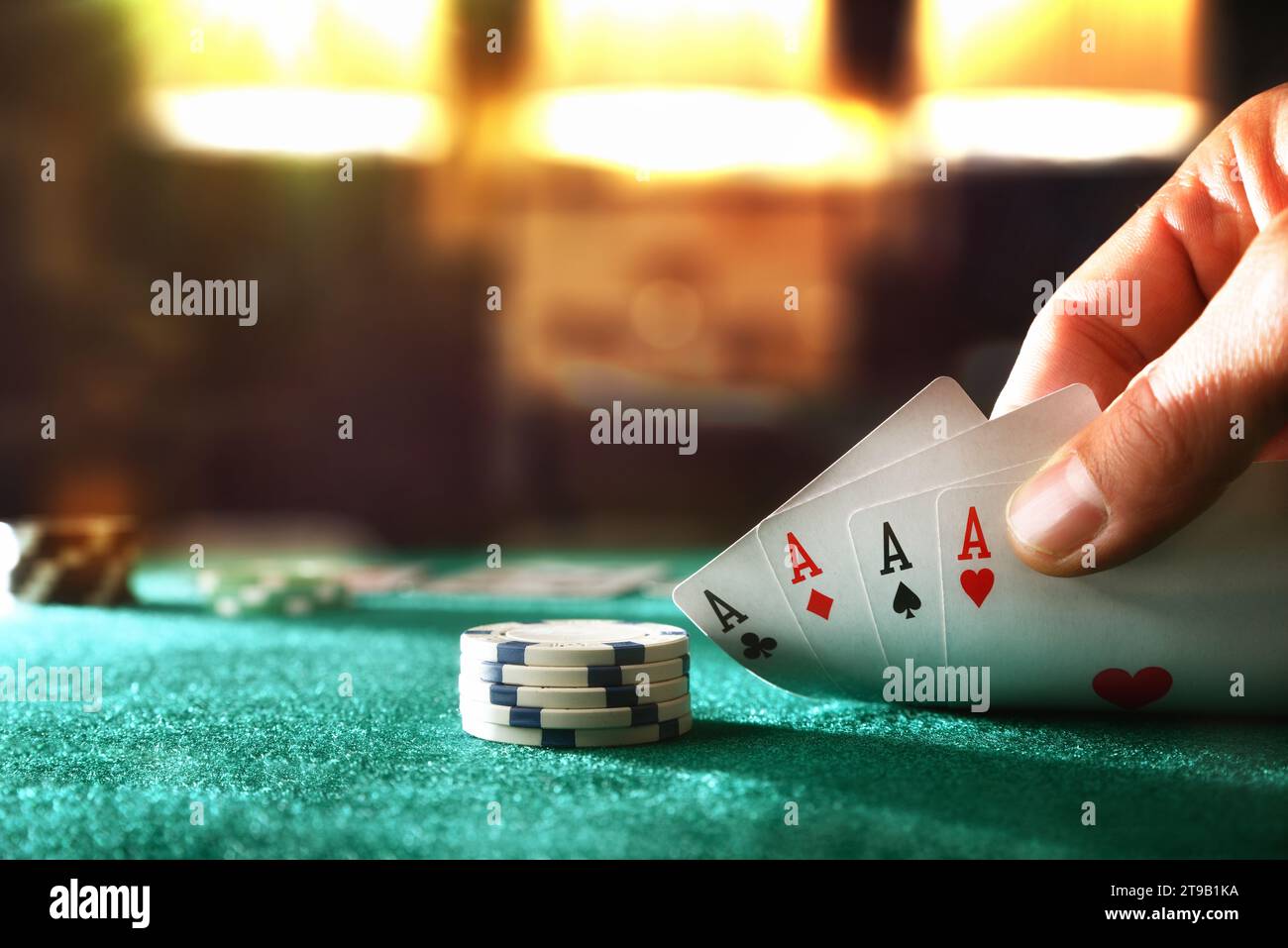 Hand zeigt vier Asse, die Karten auf einem Tisch mit grüner Matte in einer Spielhalle spielen. Vorderansicht. Stockfoto