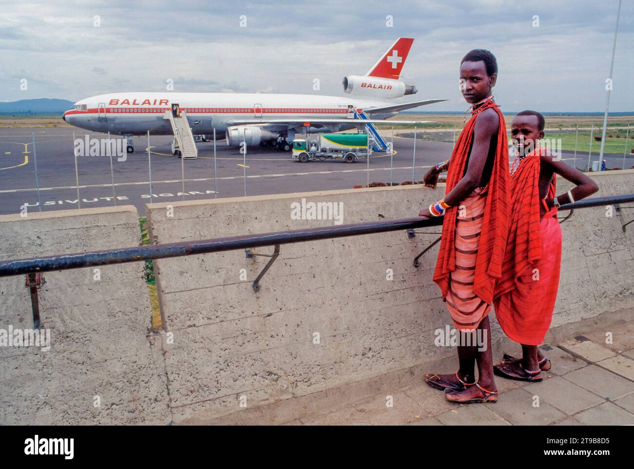 Tansania, Arusha - Maasai-Jungs schauen sich das Flugzeug am Flughafen Kilimandscharo an. Stockfoto