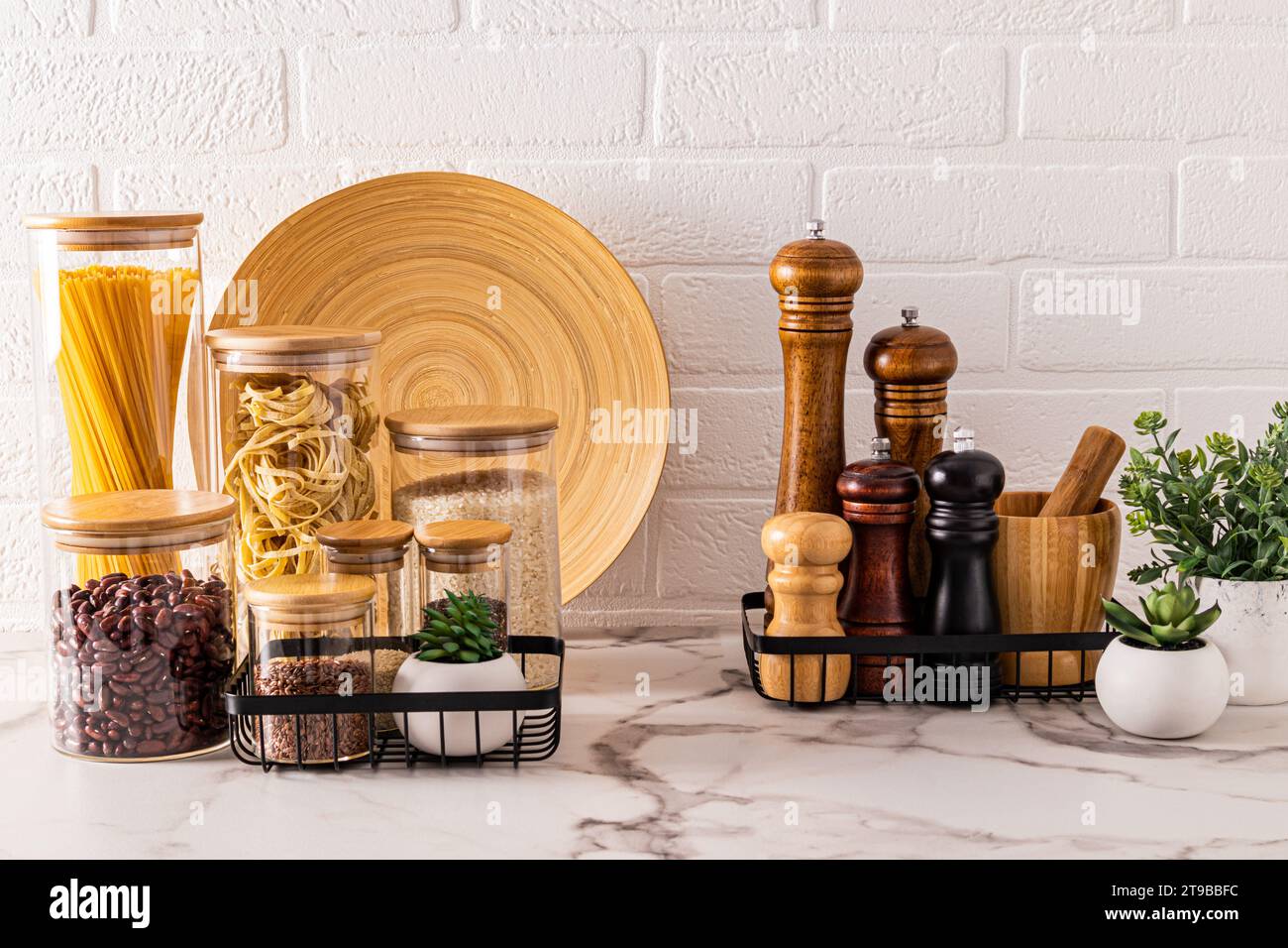 Schöner Küchenhintergrund mit Lagerbereich für Massenprodukte und Gewürze. Zimmerpflanzen für Gemütlichkeit. Vorderansicht. Weiße Ziegelwand Stockfoto