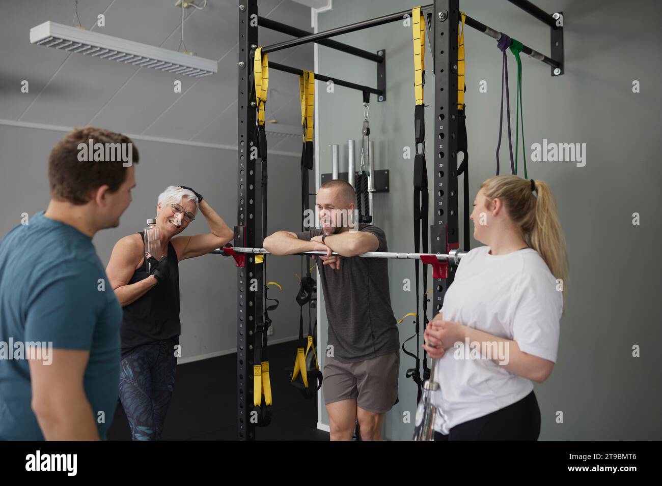 Lächelnde Leute, die im Fitnessstudio miteinander reden Stockfoto