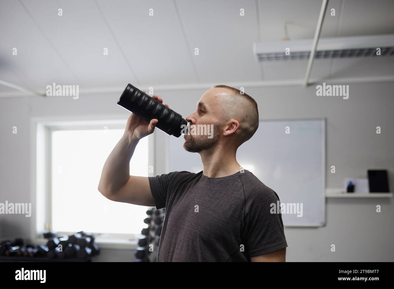 Seitenansicht des Mannes Trinkwasser im Fitnessstudio Stockfoto