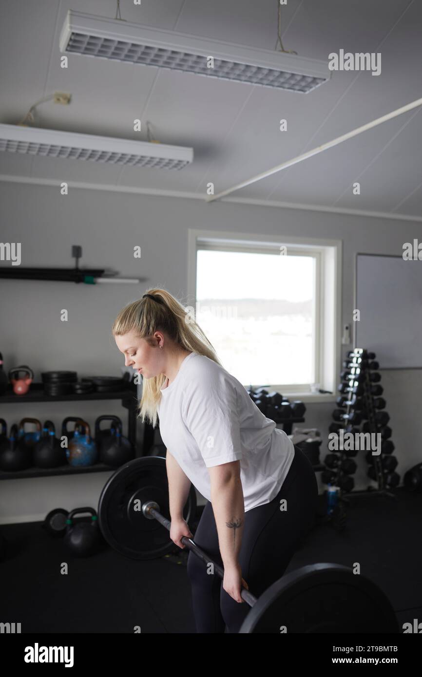 Mittelerwachsene Frau, die Langhantel im Fitnessstudio hebt Stockfoto
