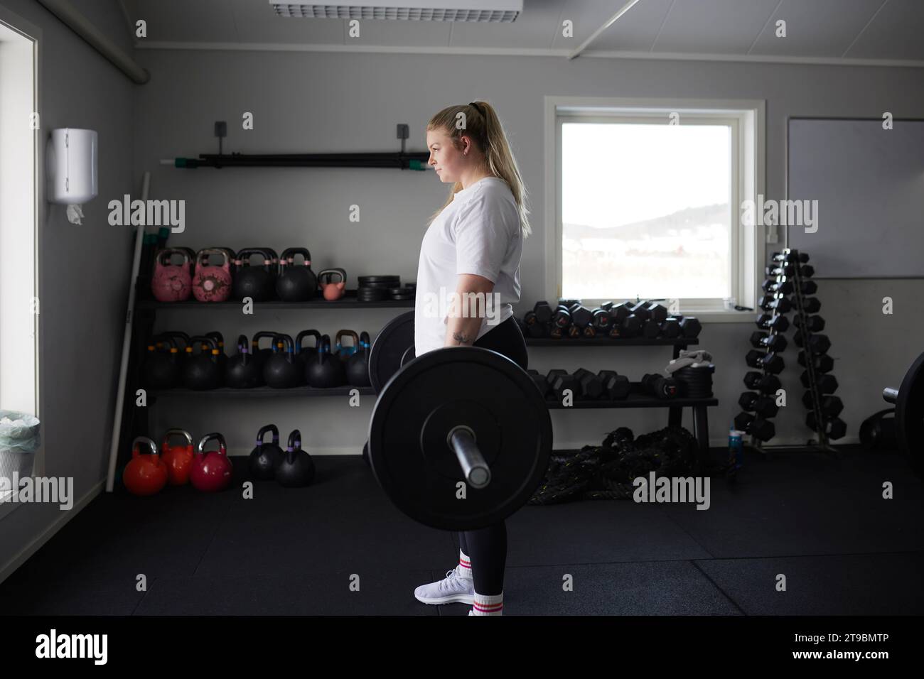 Mittelerwachsene Frau, die Langhantel im Fitnessstudio hebt Stockfoto