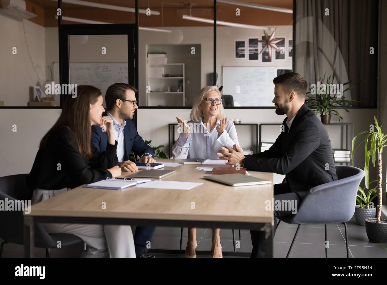 Frau der leitenden Firmeninhaberin, die mit einem Team jüngerer Manager spricht Stockfoto