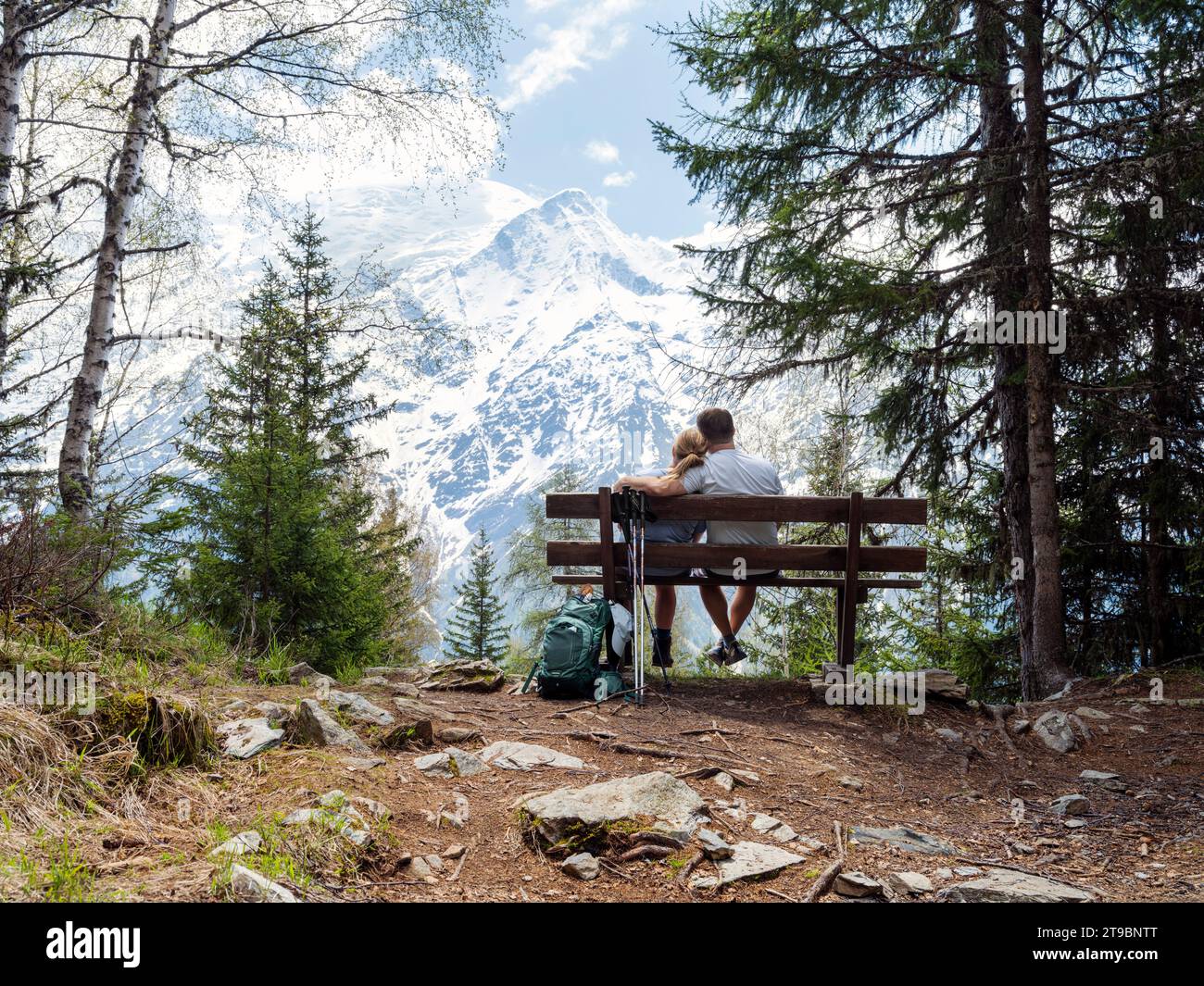 Ein Paar sitzt auf der Bank und sieht Berge an Stockfoto