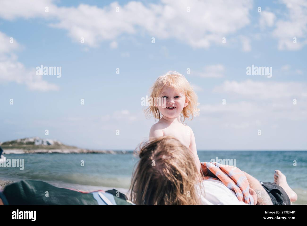 Mädchen mit Mutter, die am Strand relaxt Stockfoto