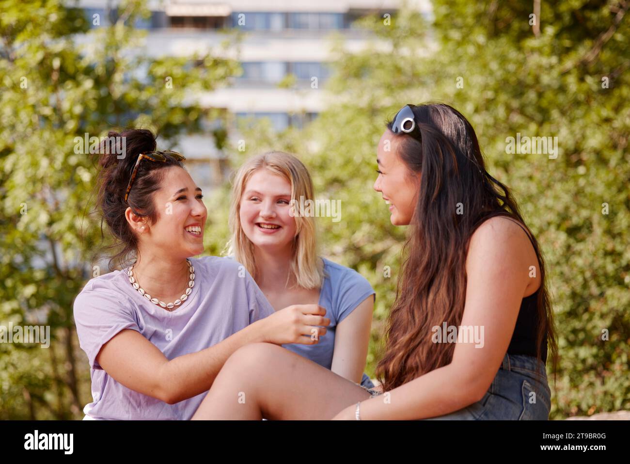 Drei junge Freundinnen sitzen zusammen und unterhalten sich Stockfoto