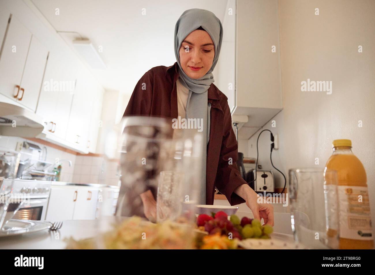 Frau im Kopftuch-Einstelltisch für eid al-fitr zu Hause Stockfoto