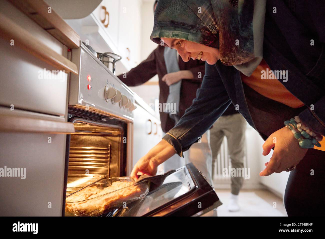 Frau, die Essen für eid al-fitr aus dem Ofen nimmt Stockfoto