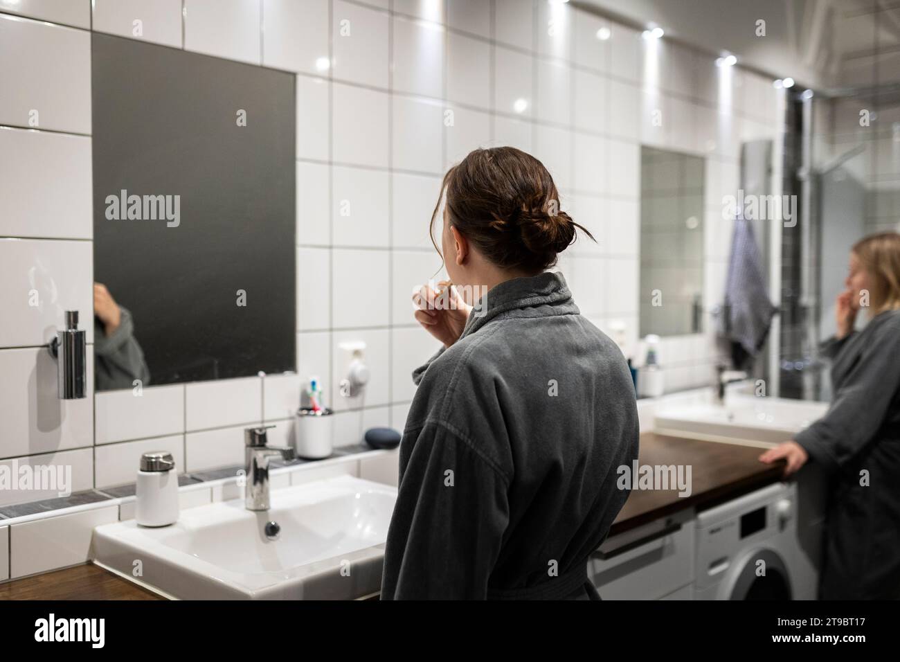 Rückansicht einer jungen Frau beim Zähneputzen im Badezimmer Stockfoto