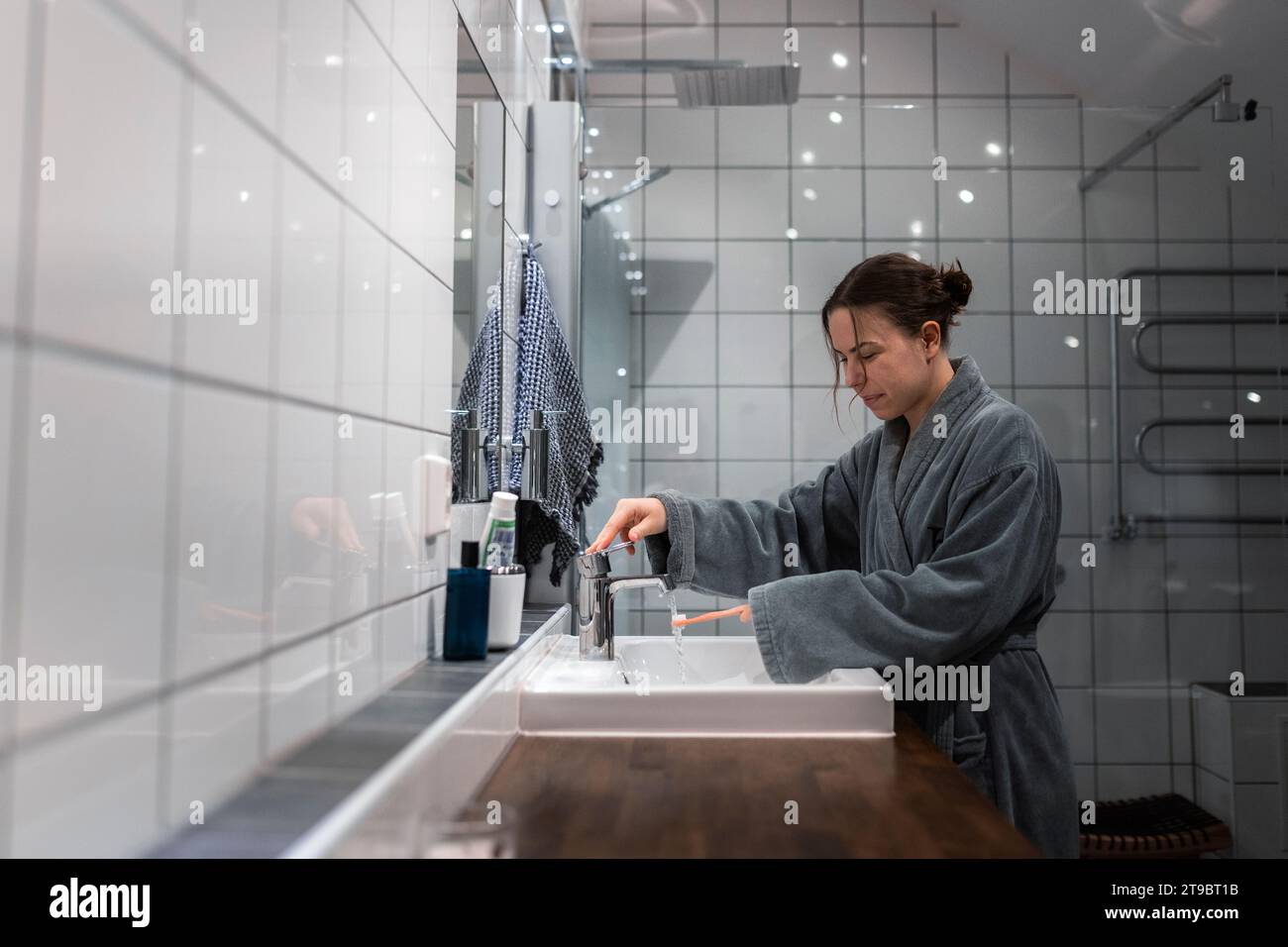 Seitenansicht einer jungen Frau, die im Waschbecken im Bad Zahnbürste wäscht Stockfoto