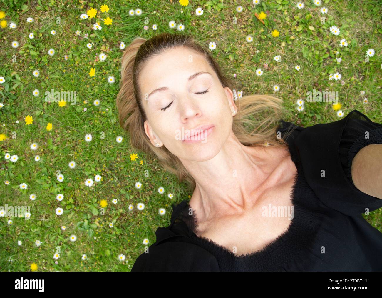 Direkt über dem Blick einer Frau, die mit geschlossenen Augen auf dem Gras liegt Stockfoto