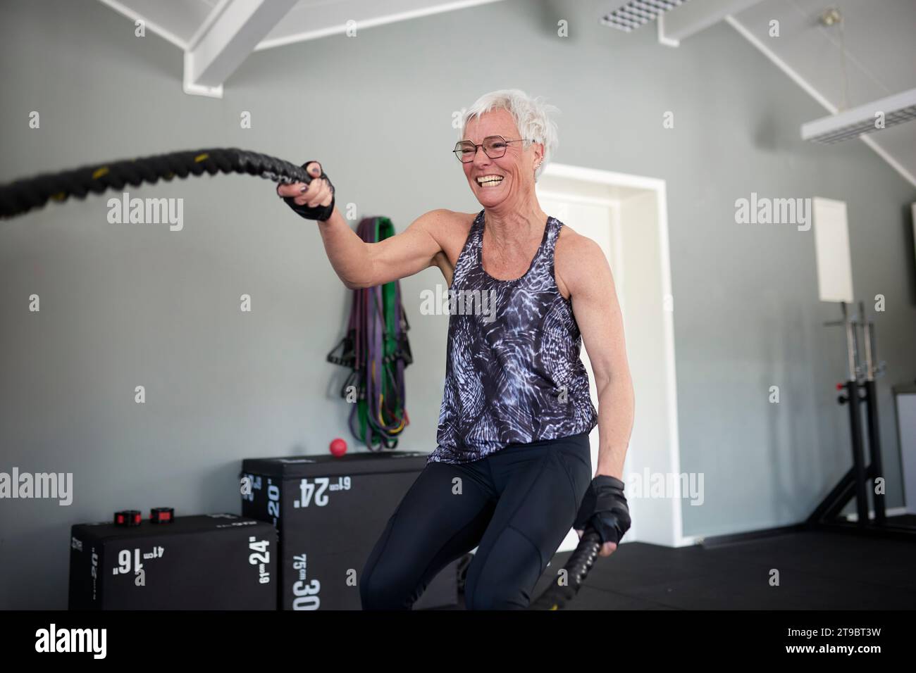 Glückliche aktive Seniorin, die mit Seilen im Gesundheitsclub trainiert Stockfoto