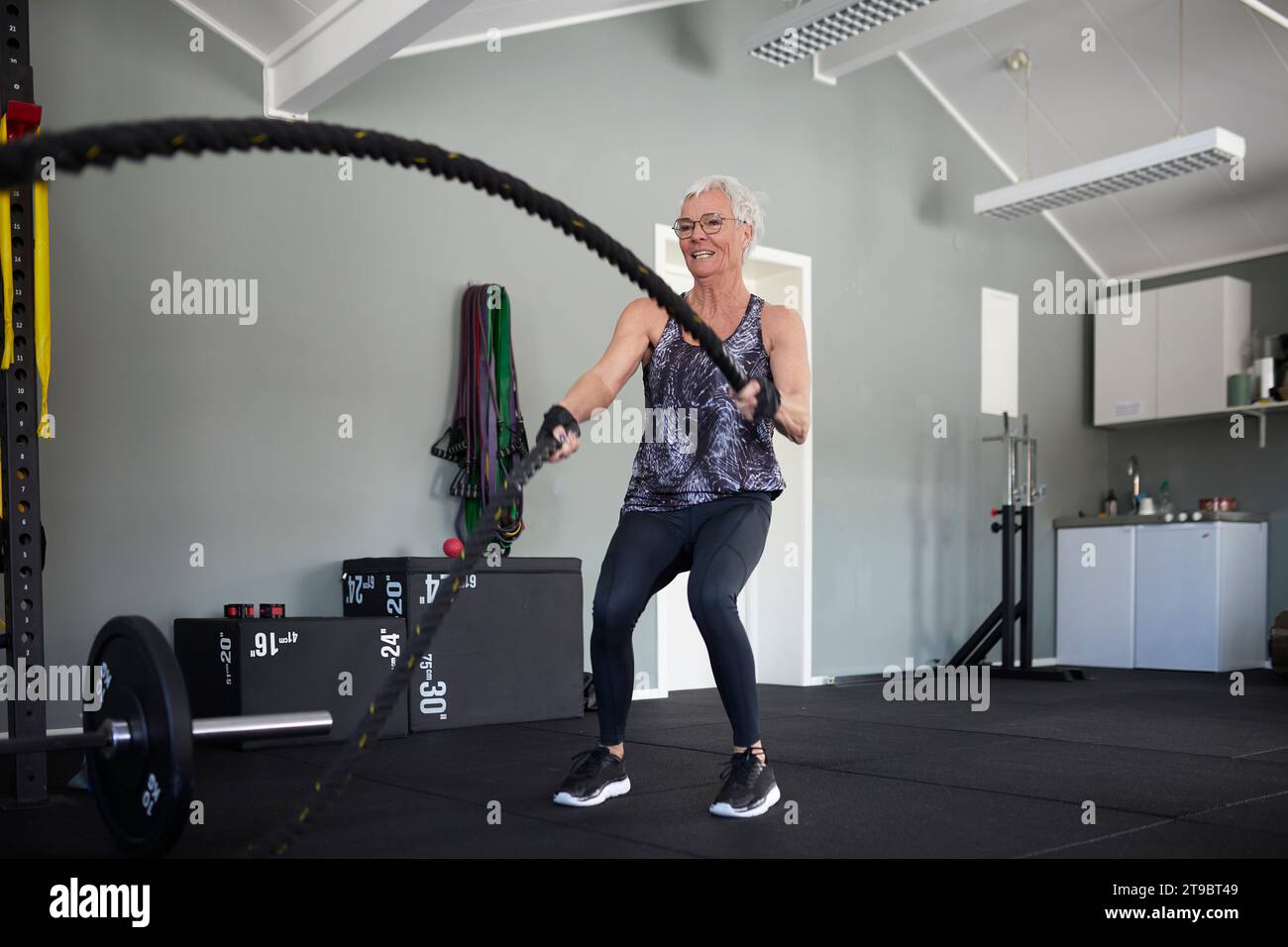Die volle Länge einer aktiven Seniorin, die mit Seilen im Health Club trainiert Stockfoto