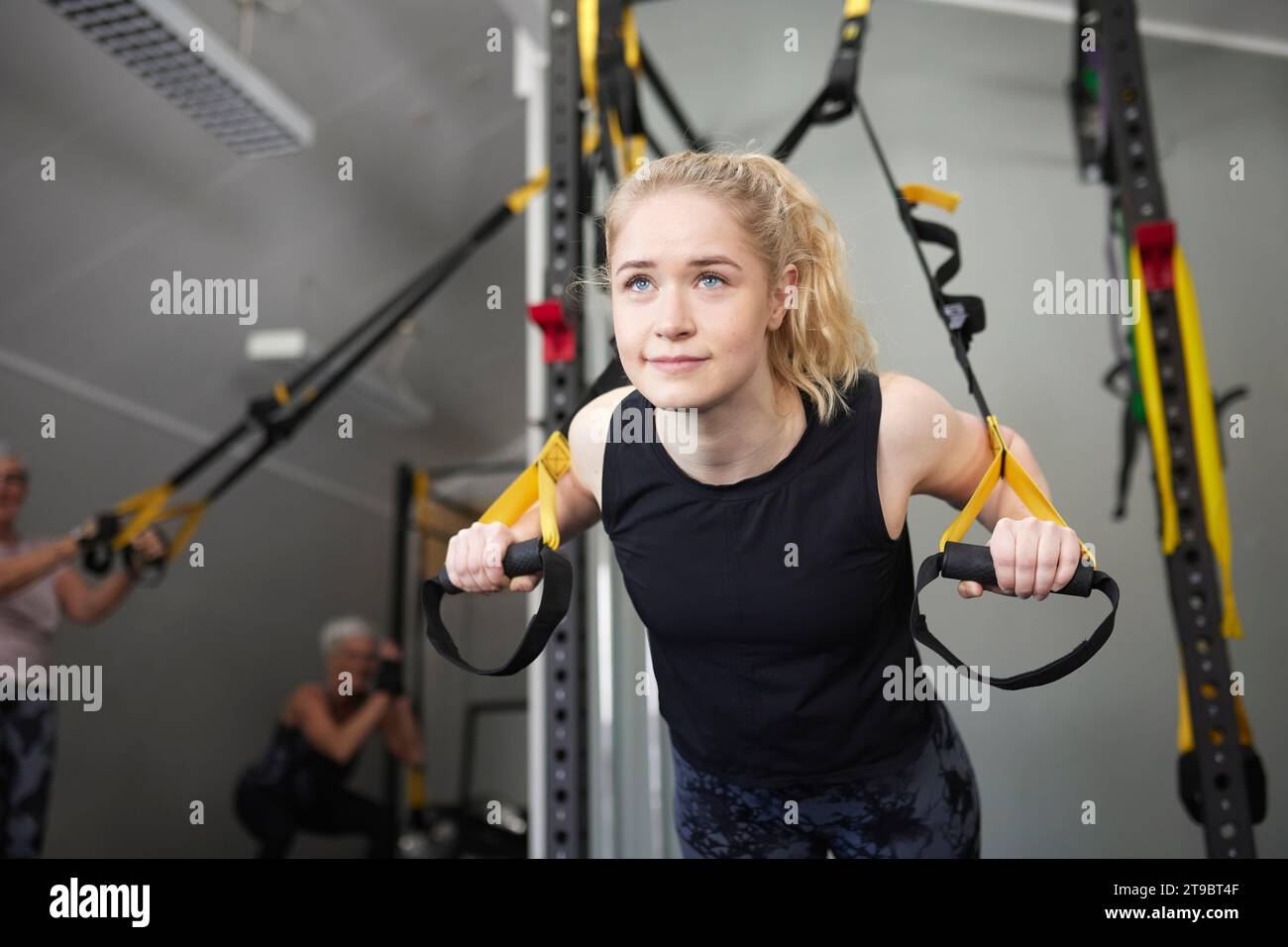 Junge Frau, die sich auf Turnringe im Gesundheitsclub stützt Stockfoto