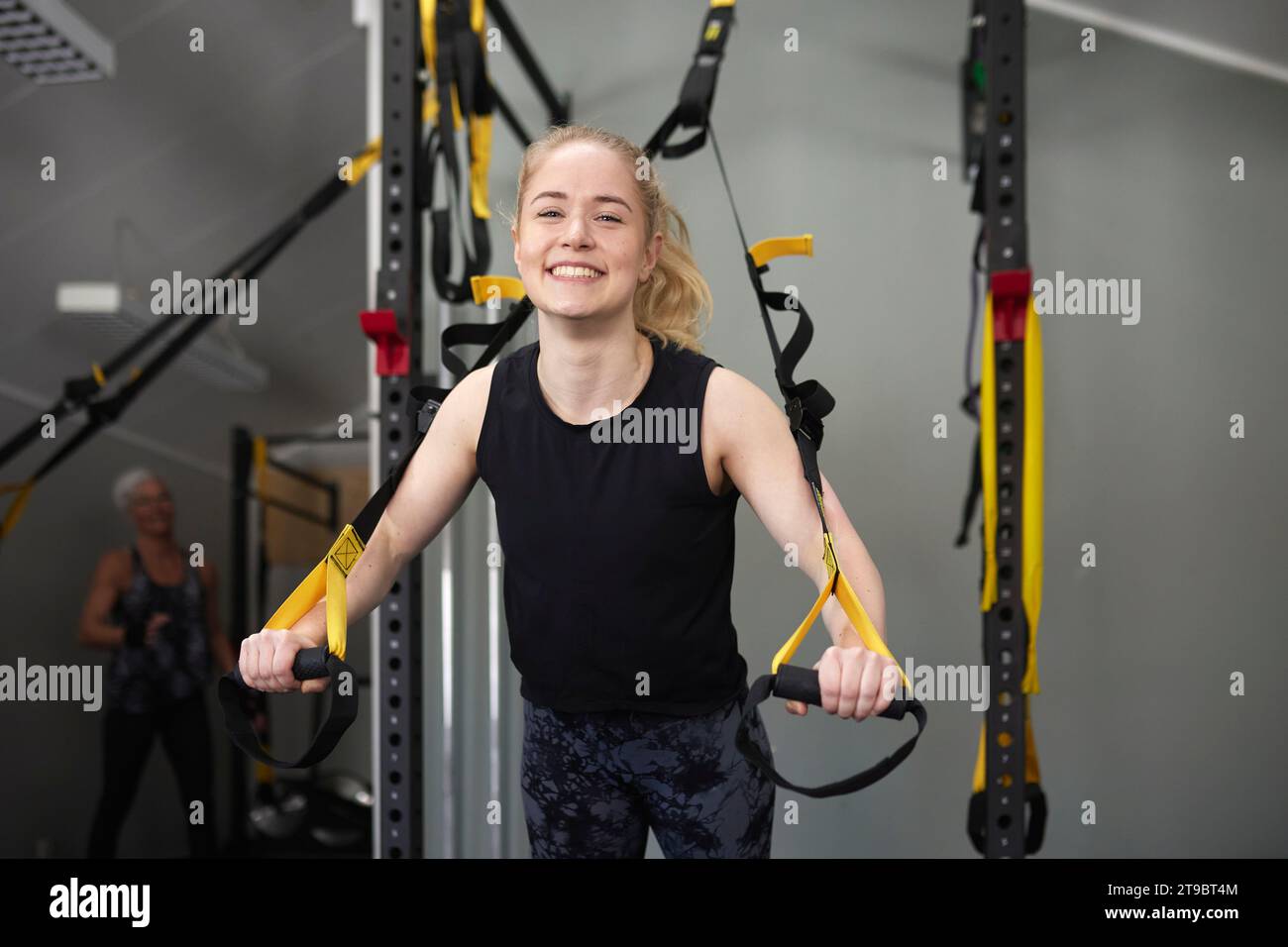 Porträt einer glücklichen jungen Frau, die sich auf Turnringe im Gesundheitsclub stützt Stockfoto
