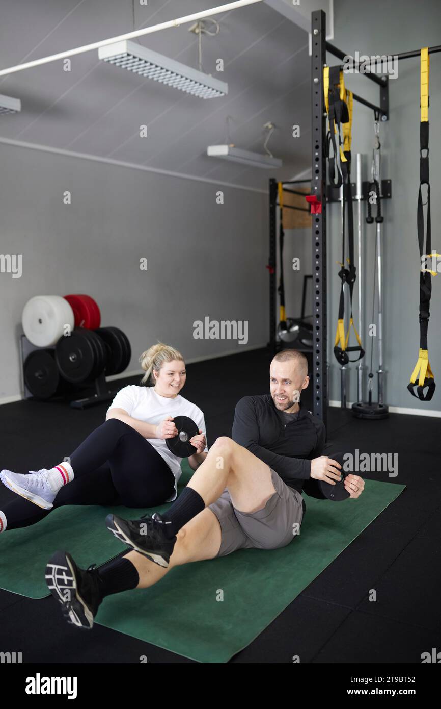 Glückliches Paar im mittleren Erwachsenenalter, das mit Gewichten im Fitnessclub trainiert Stockfoto