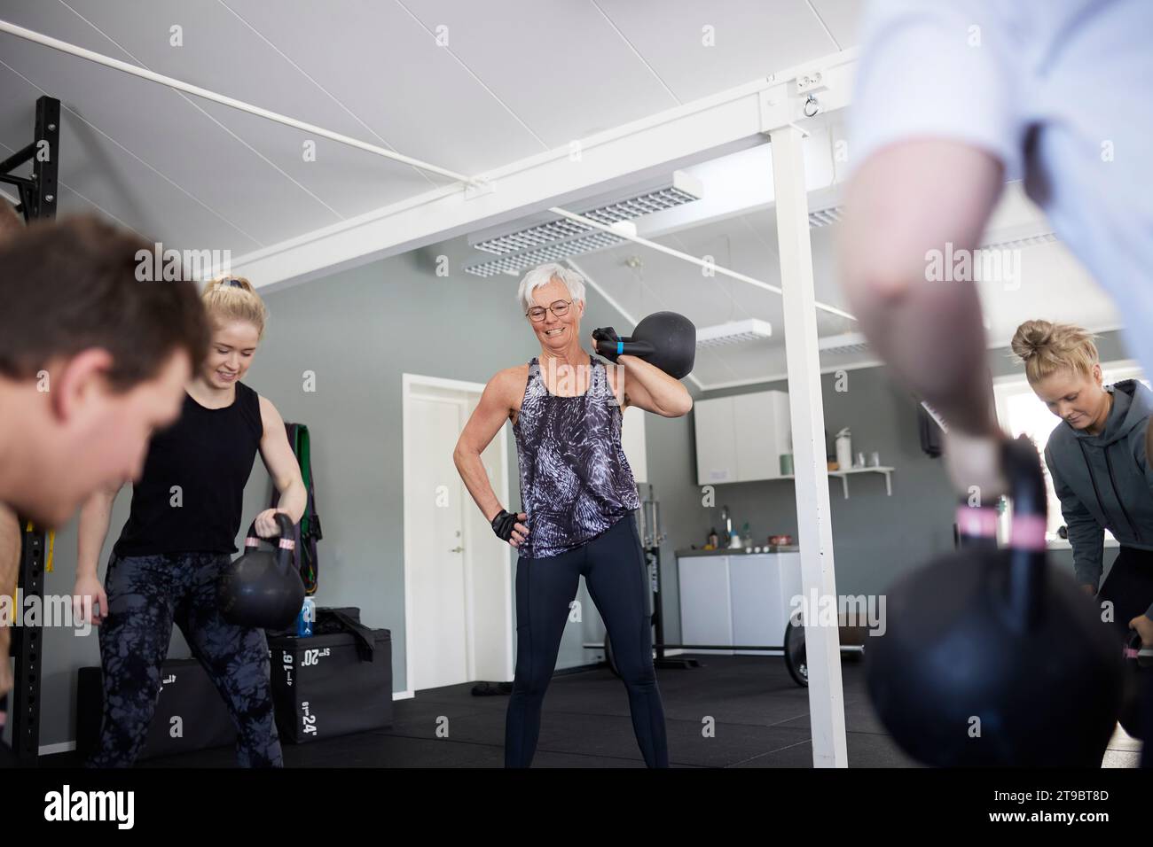 Seniorin, die mit Leuten im Fitnessstudio trainiert Stockfoto