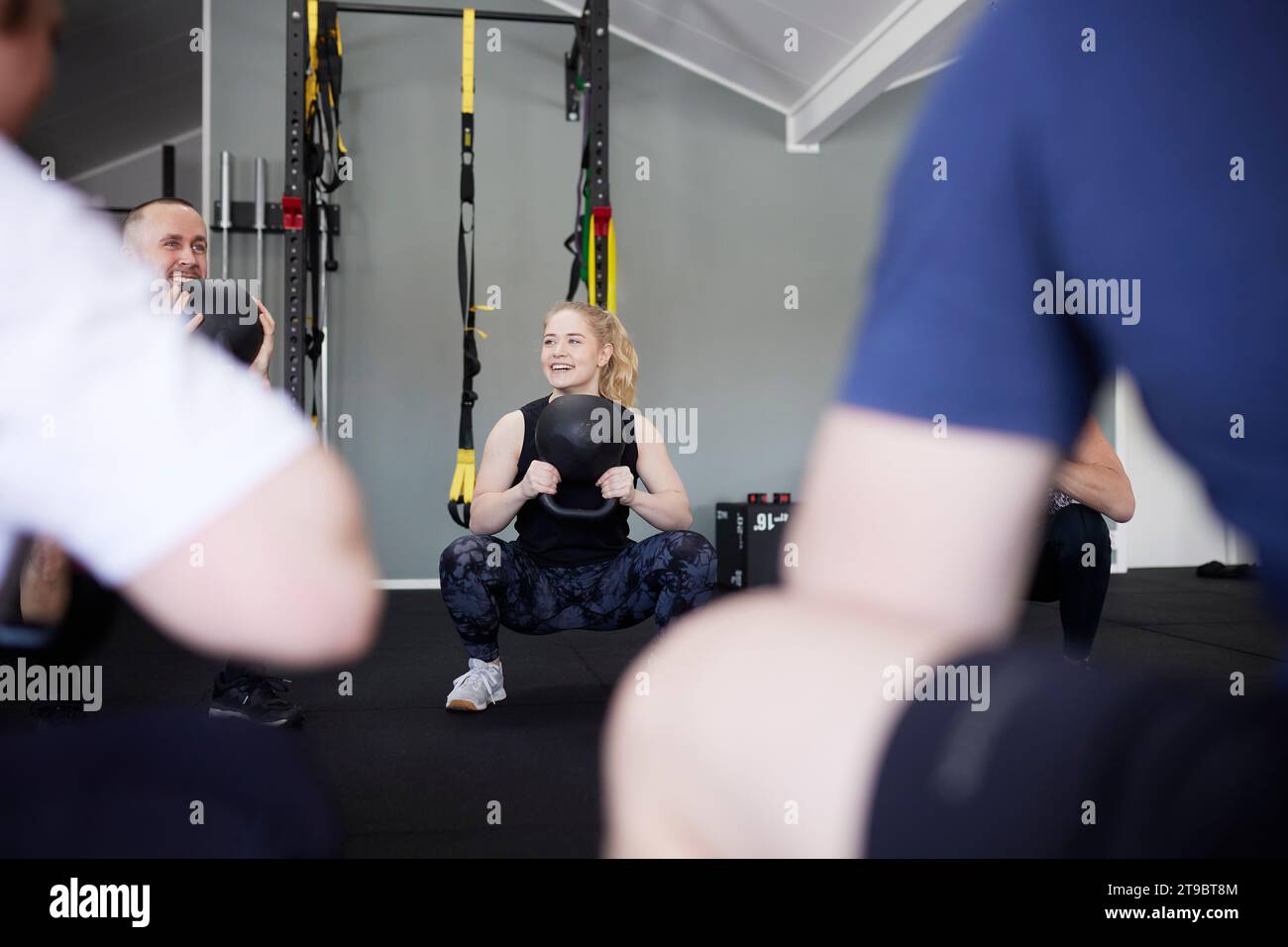 Lächelnde Menschen, die im Fitnessstudio mit Kettlebells trainieren Stockfoto