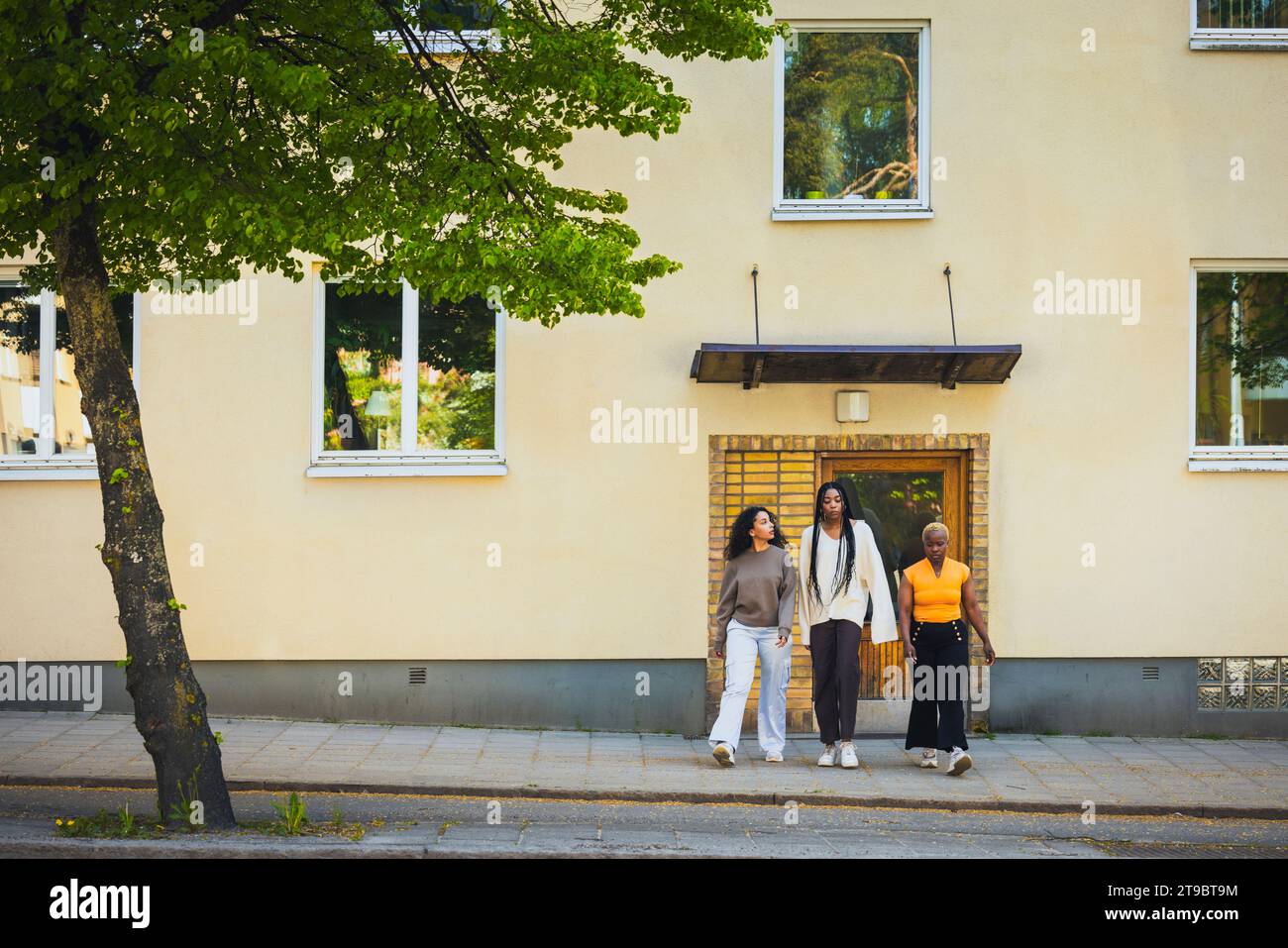 Junge Frauen, die auf Gehwegen gegen Bauen laufen, während sie am Wochenende abhängen Stockfoto