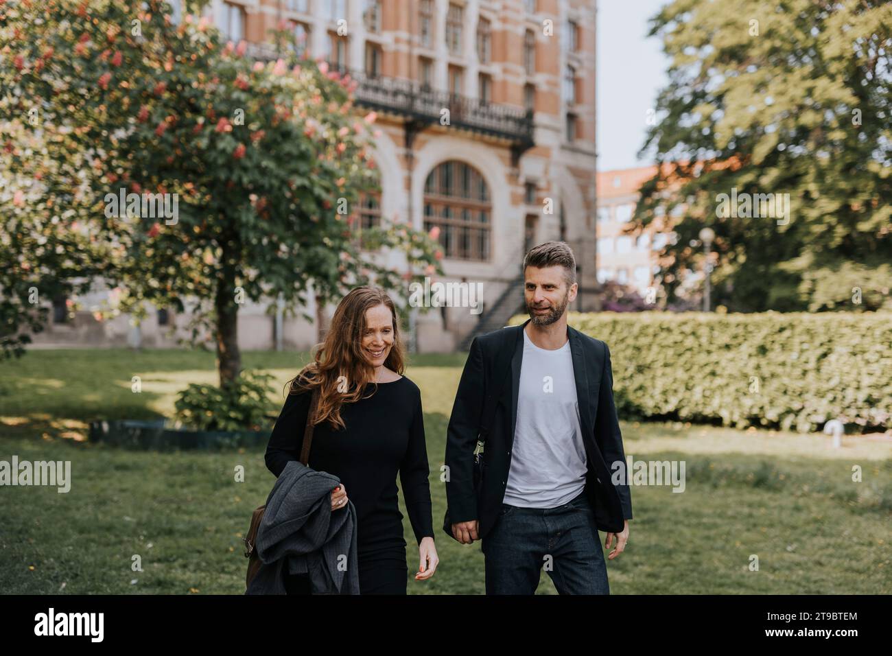 Weibliche und männliche Kollegen unterhalten sich beim gemeinsamen Spaziergang in der Stadt Stockfoto
